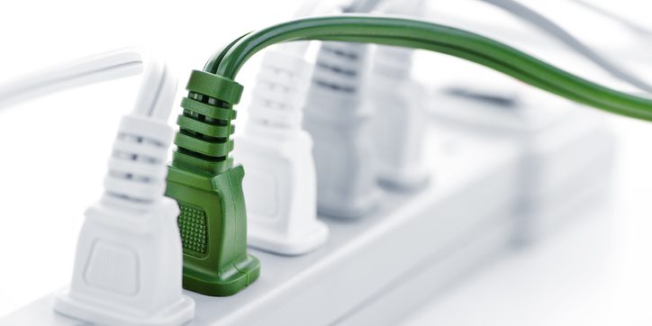Green power cord plugged into a power strip, illustrating energy vampire concept related to electricity consumption.
