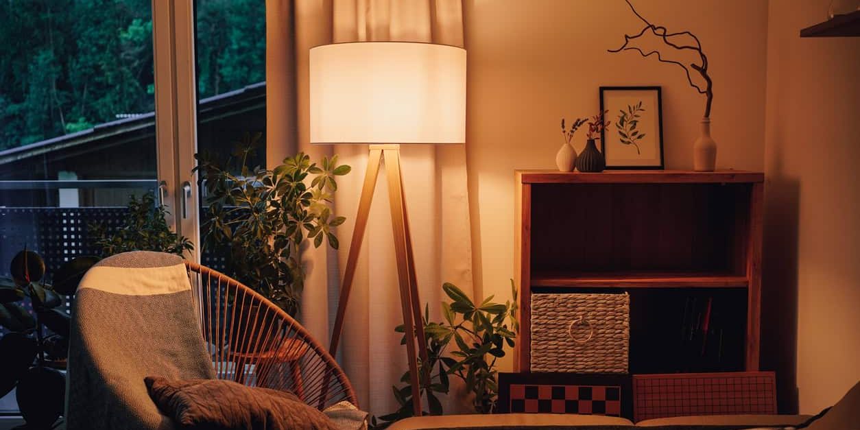 View of tripod lamp in a cozy living room spending warm light flickering lights can be an electrical safety issue.